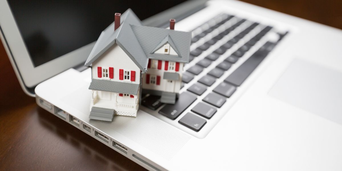 Model house on a laptop keyboard, symbolizing a digital real estate franchise.