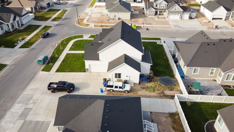 Person stands at a fork in a clean suburban road, symbolizing a home seller's dilemma when choosing between real estate ag...