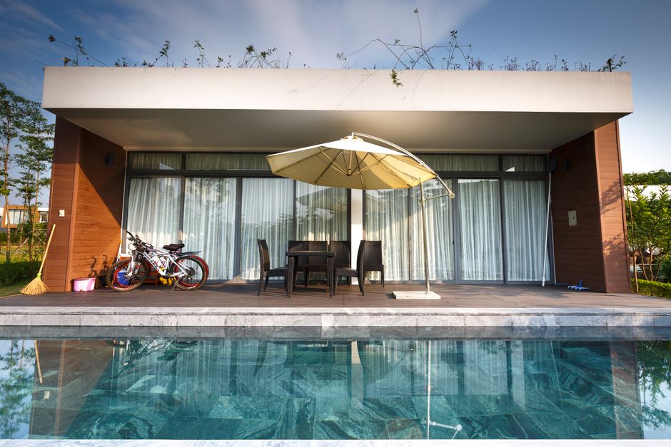 The beautiful exterior of a modern luxury home in Atlanta with a pristine swimming pool on a bright, sunny day.