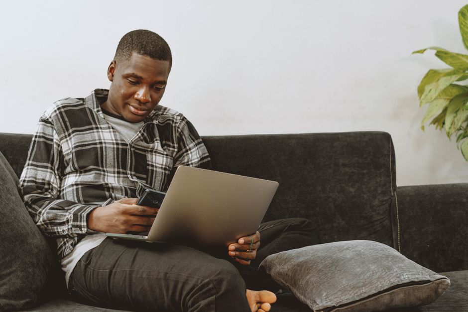Professionally dressed real estate agent strategizes on a laptop inside a bright, modern living room of a luxury home.