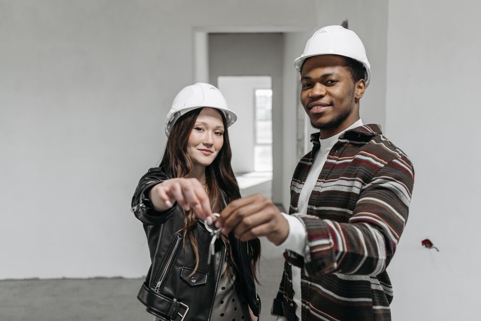 A real estate agent hands the keys to a happy couple in front of their new, modern Atlanta home, representing a successful property transaction.